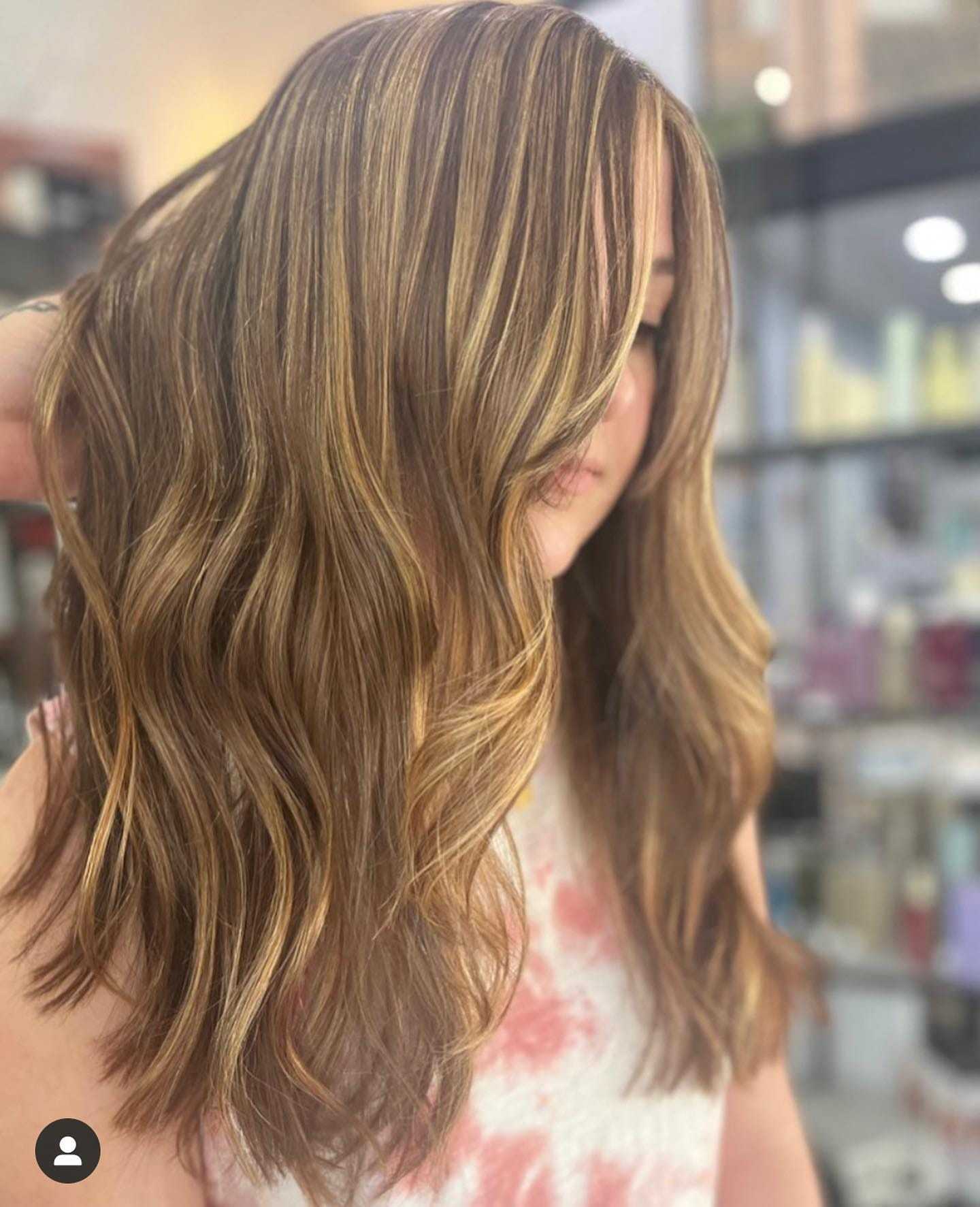 Woman with long wavy hair featuring blonde highlights in a salon.