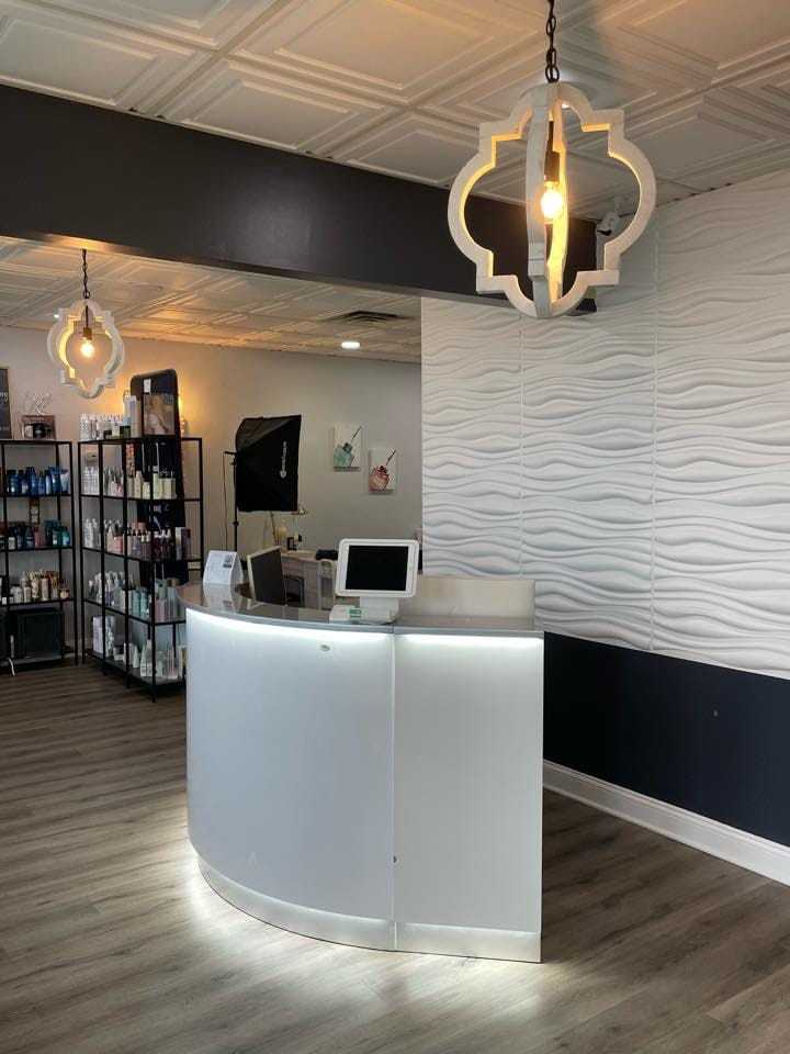 Modern salon reception area with stylish hanging lights and a sleek, curved front desk.