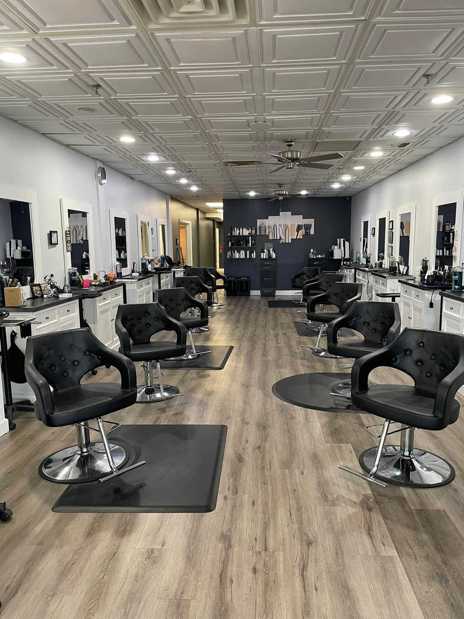 Modern, stylish hair salon with black chairs, mirrors, and wooden flooring.