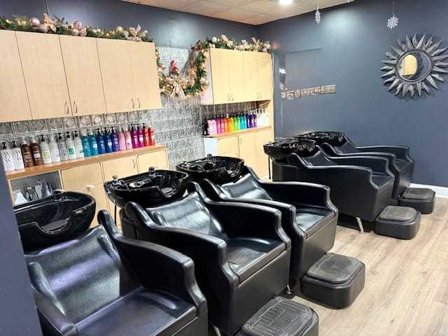 Modern salon with black shampoo chairs, colorful hair products, and festive holiday decorations.