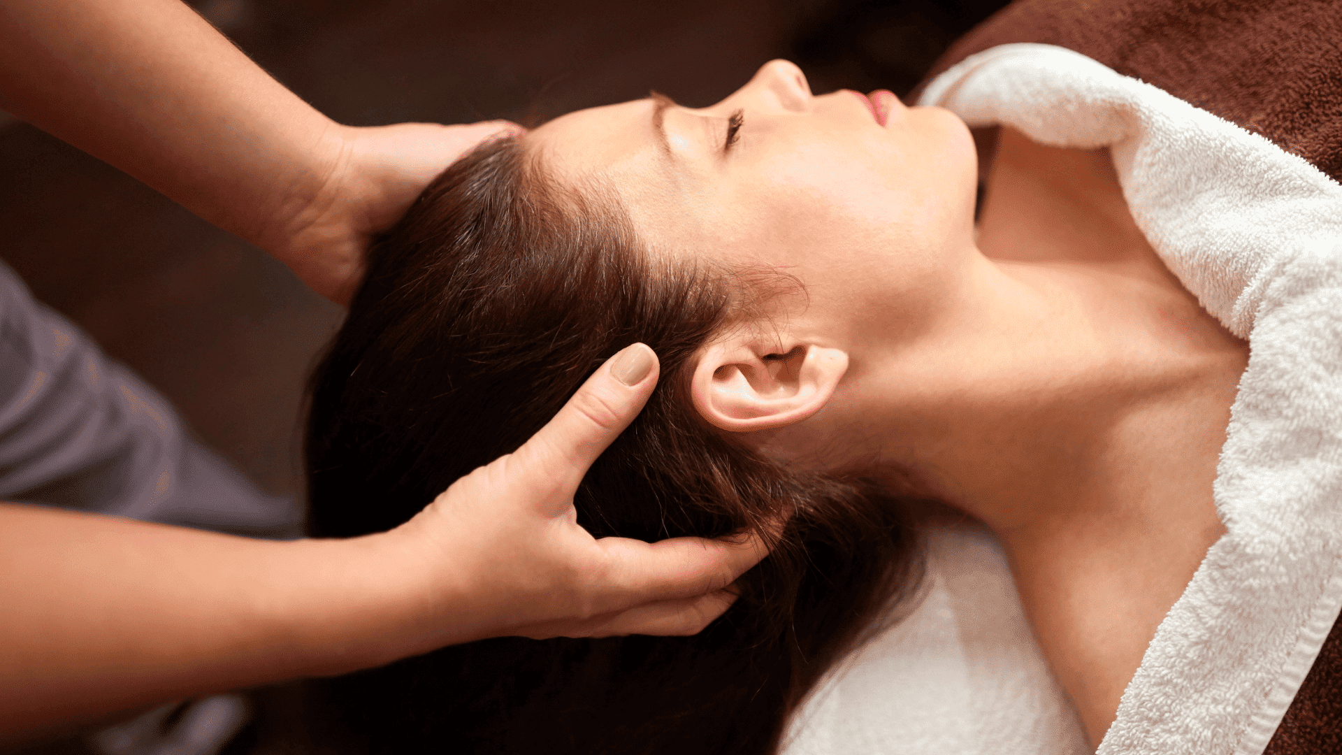 Woman enjoying relaxing head massage at a spa.