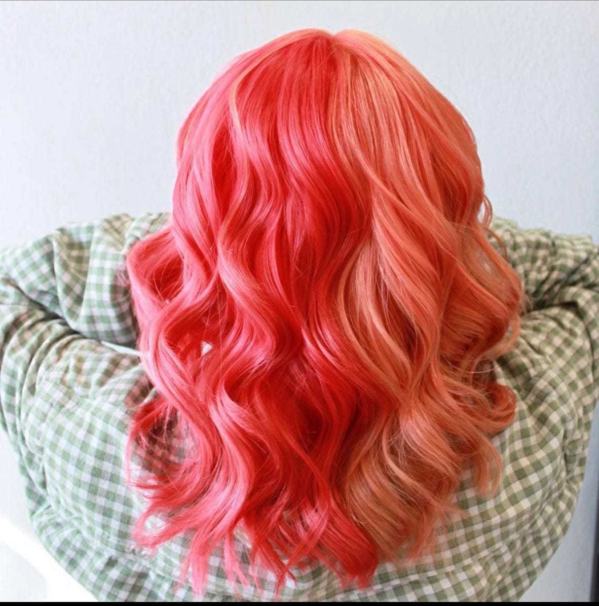 Back view of a person with long, wavy hair dyed in bright red and peach tones.